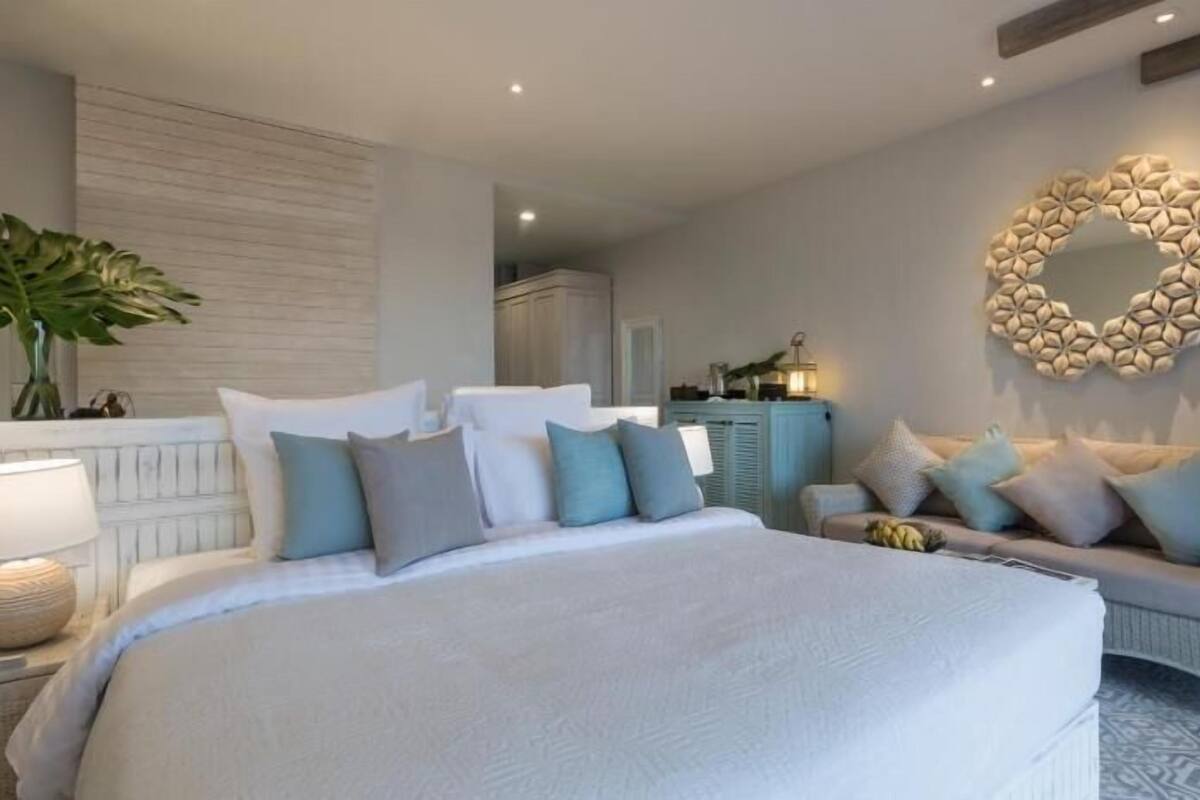 Une chambre avec un grand lit, un canapé, un élément décoratif mural et une plante.