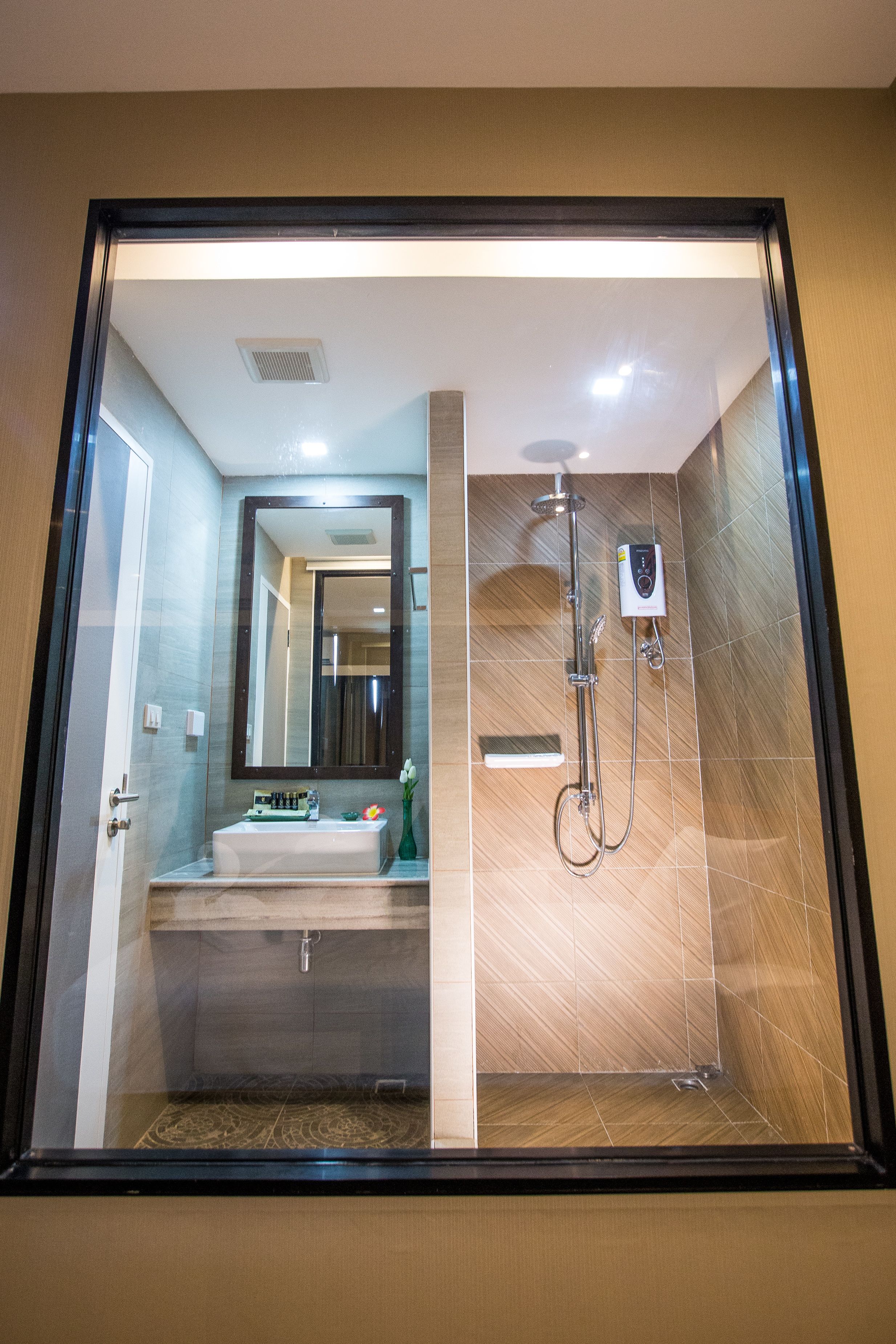 A modern bathroom with a glass-enclosed shower, a large mirror, and a vanity with a sink and toiletries.