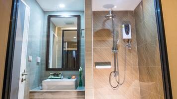 A modern bathroom with a glass-enclosed shower, a large mirror, and a vanity with a sink and toiletries.