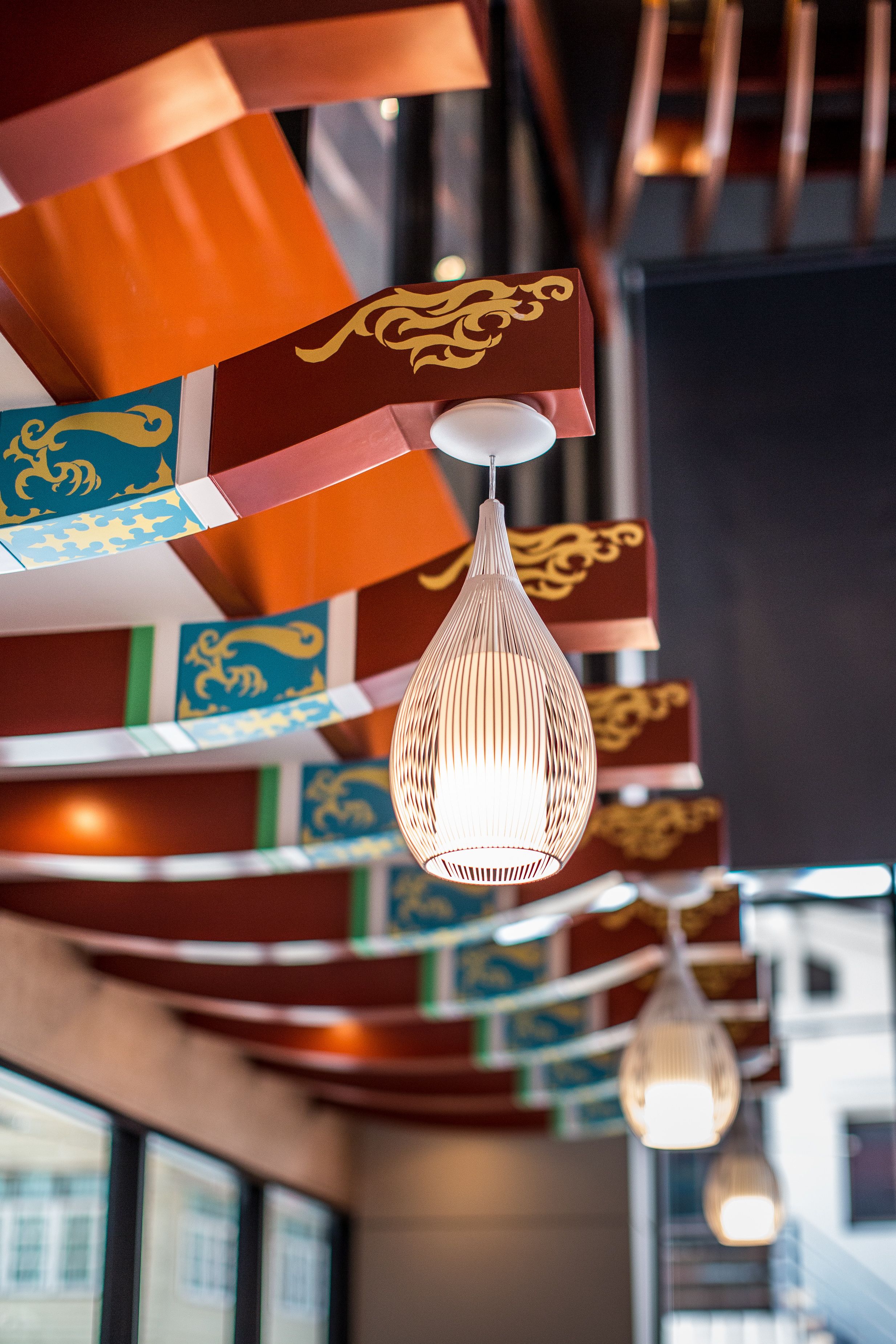 Luminária pendente com design em relevo, suspensa em teto com painéis decorativos com desenhos dourados.