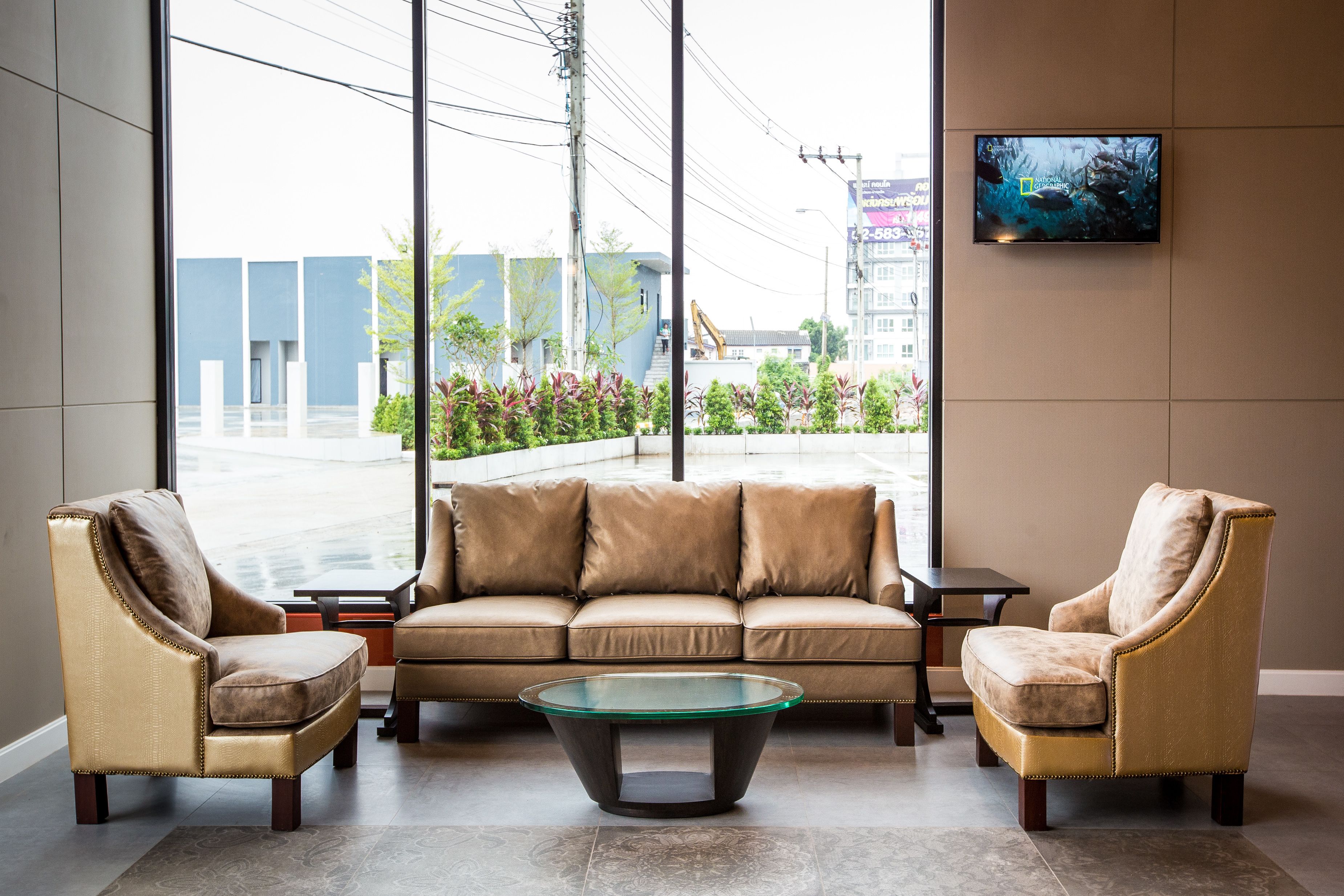 A modern interior with a beige sofa, two armchairs, and a glass coffee table.