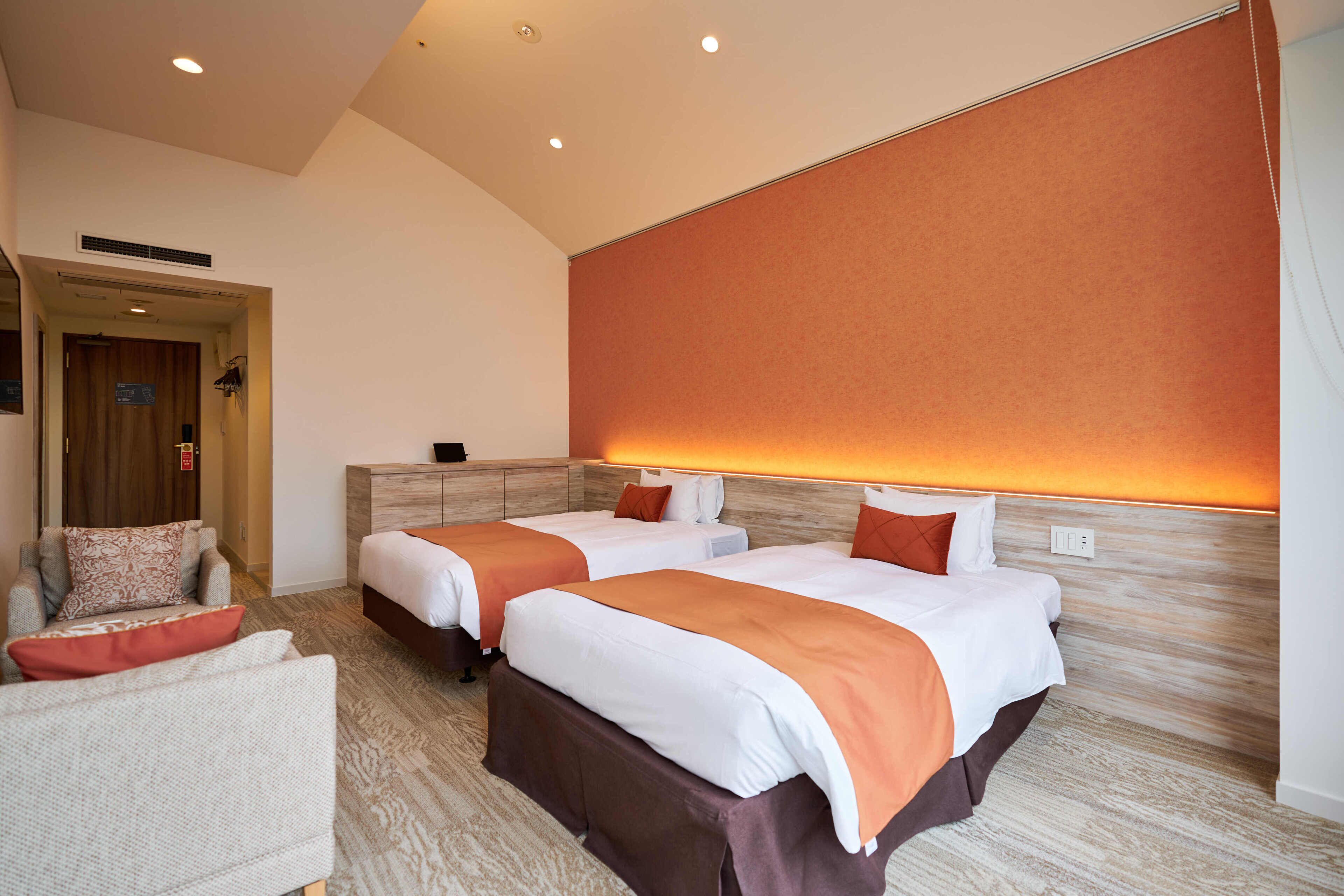 Ein Hotelzimmer mit zwei Betten, einer Couch und einem Holzkopfstück.
