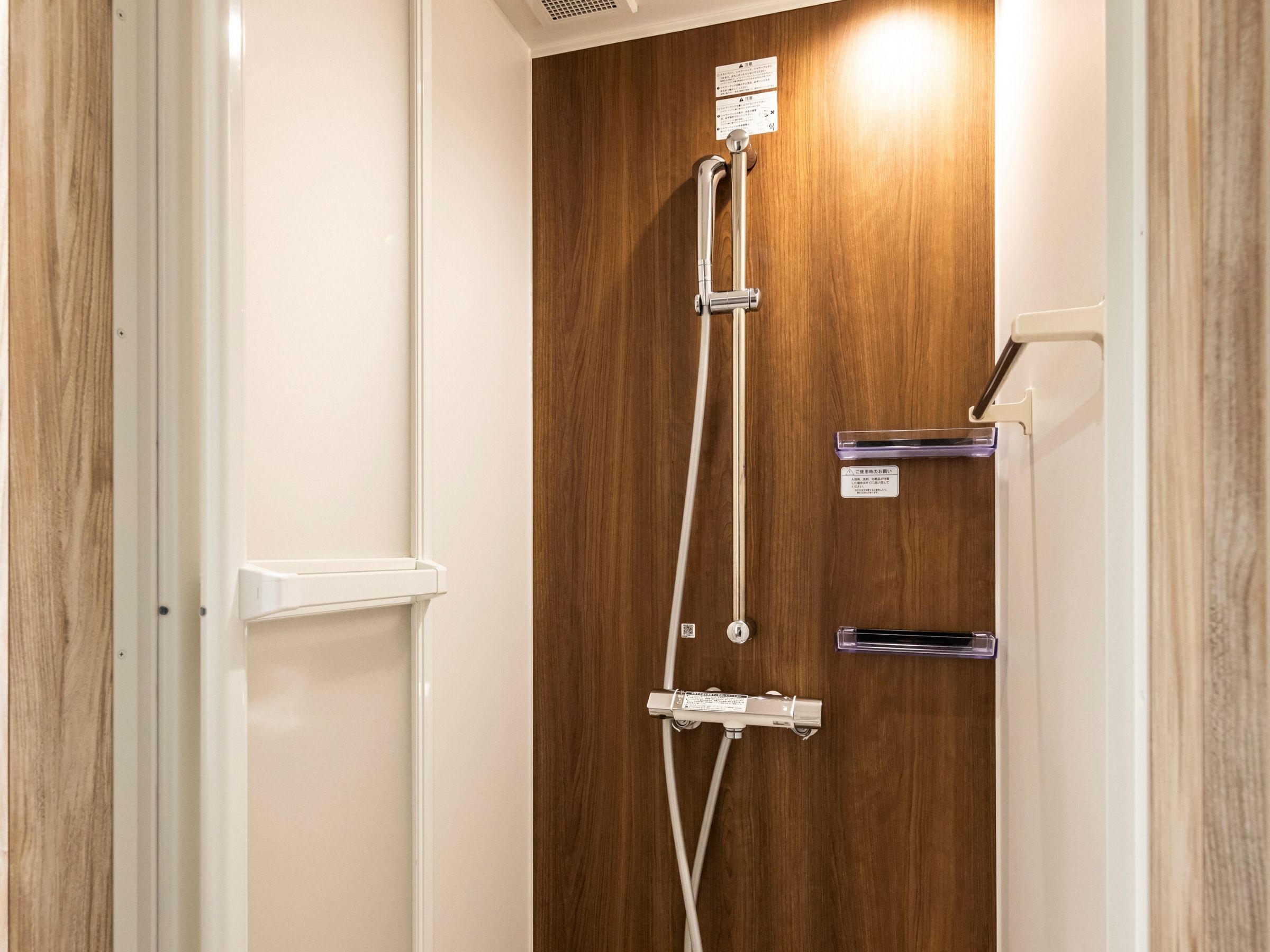 A wooden door with a shower control panel and a handrail.