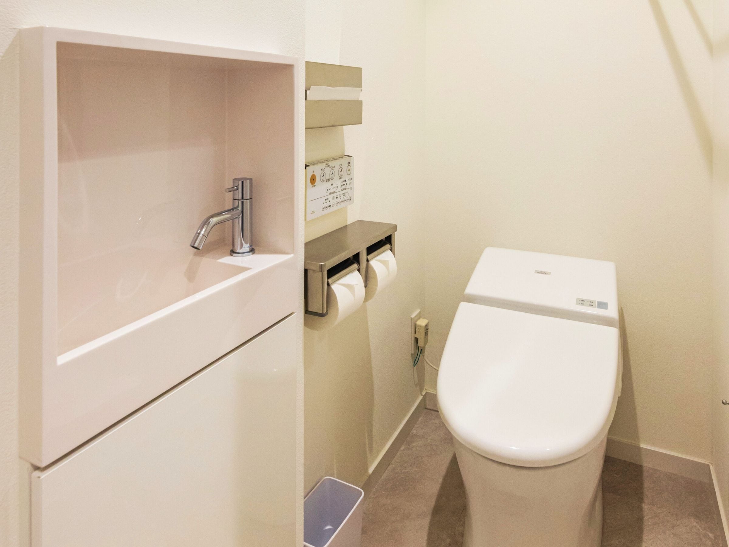 A small bathroom with a white sink, a toilet, and a paper towel dispenser.