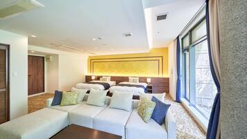 A hotel room with a large sofa set, a coffee table, and a bed with multiple pillows.