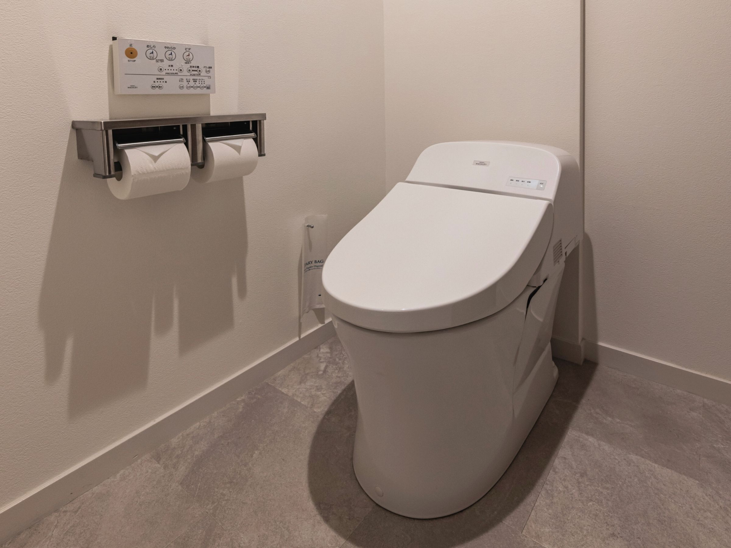 Des toilettes modernes dotées d’un panneau de commande, d’un distributeur de papier toilette et d’un sèche-mains.