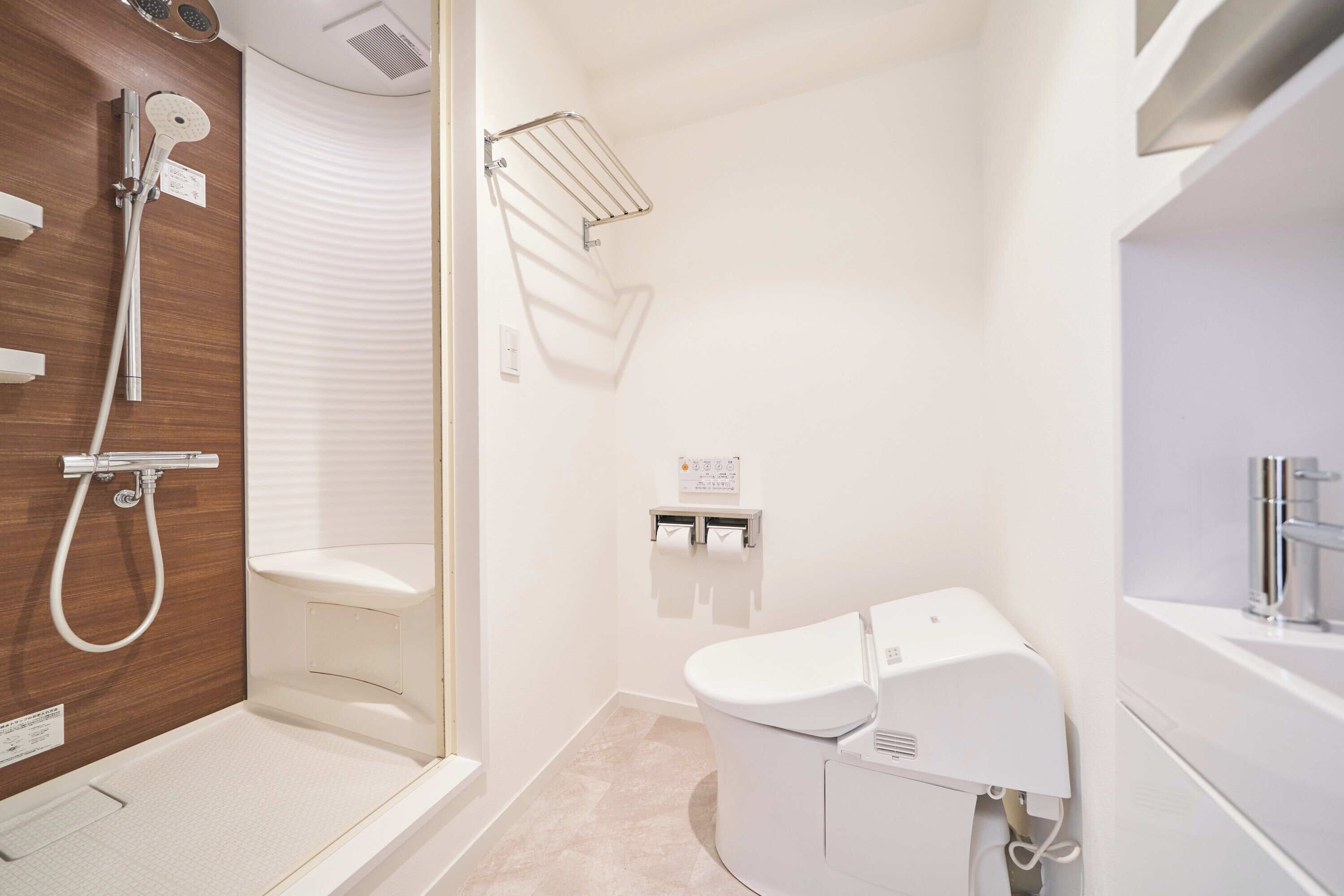 A modern bathroom with a shower, toilet, and a hand dryer.