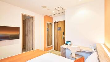 Una habitación de hotel con cama, un escritorio con ordenador y una puerta que da a otra estancia.