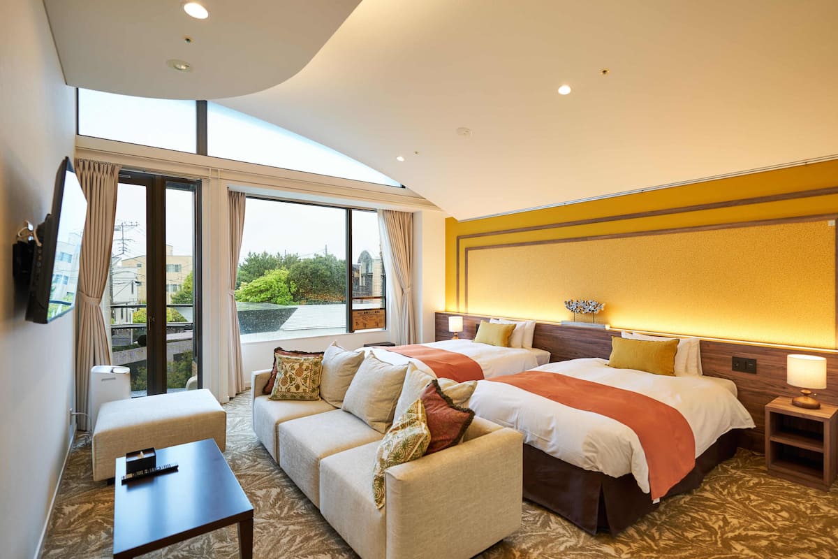 Een hotelkamer met twee bedden, een bank, een tafeltje en een televisie.