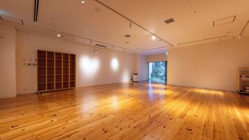 A spacious room with wooden flooring, a large window, and a built-in wooden shelving unit.