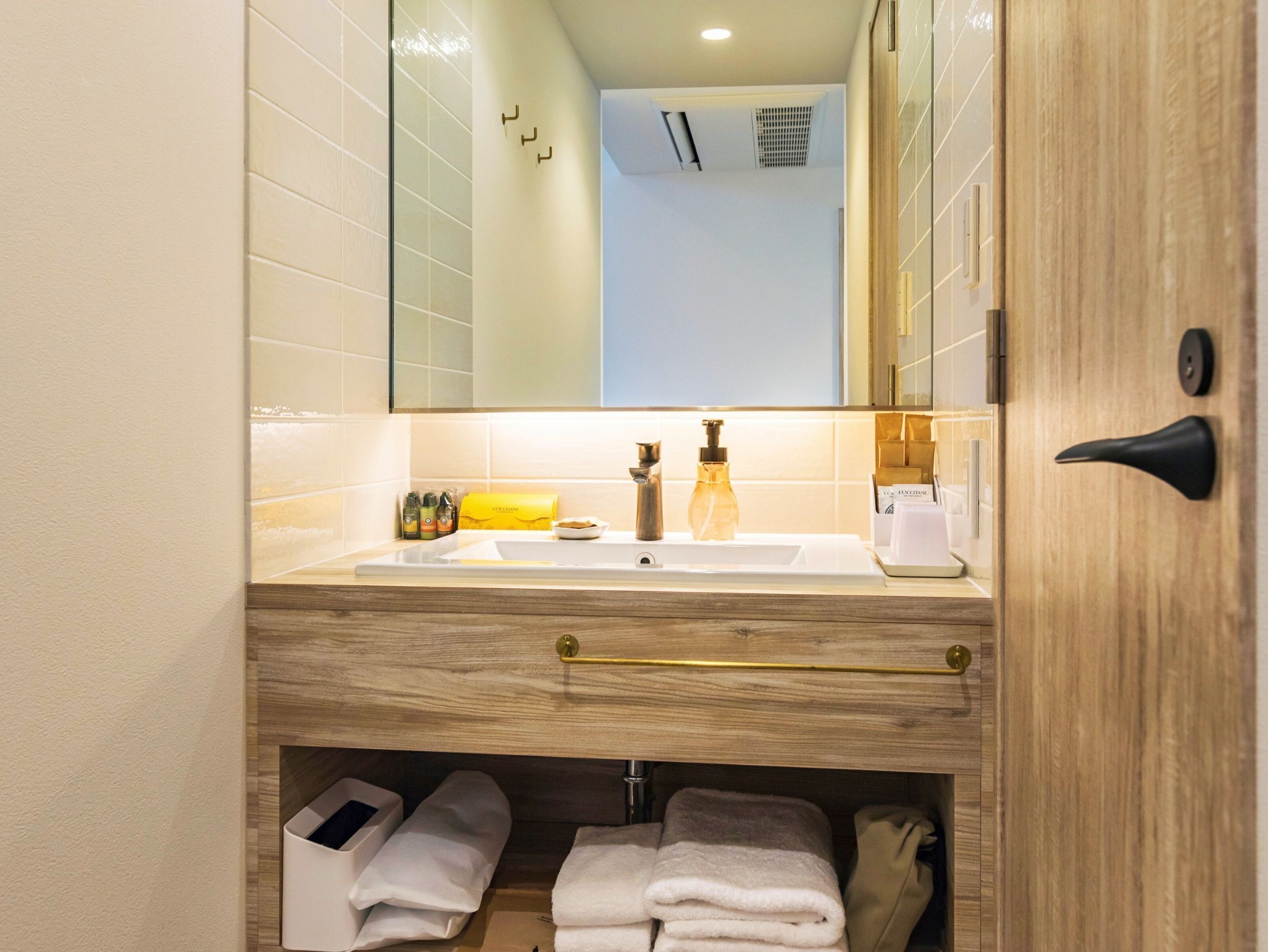 A bathroom with a wooden vanity, a sink, a mirror, and a towel rack.