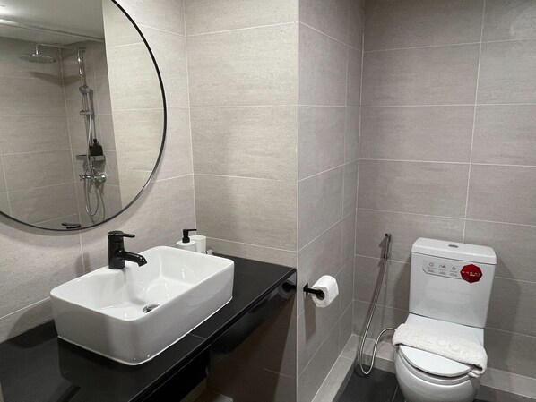 A modern bathroom with a white sink, a mirror, a toilet, and a shower.