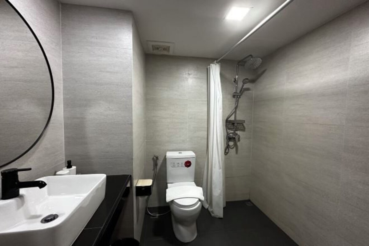 Une salle de bain moderne avec un lavabo, des toilettes et une douche, le tout de couleur blanche.
