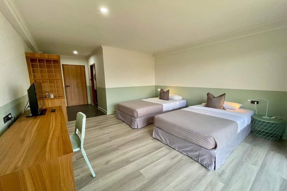 A hotel room with two beds, a desk, a chair, and a TV.