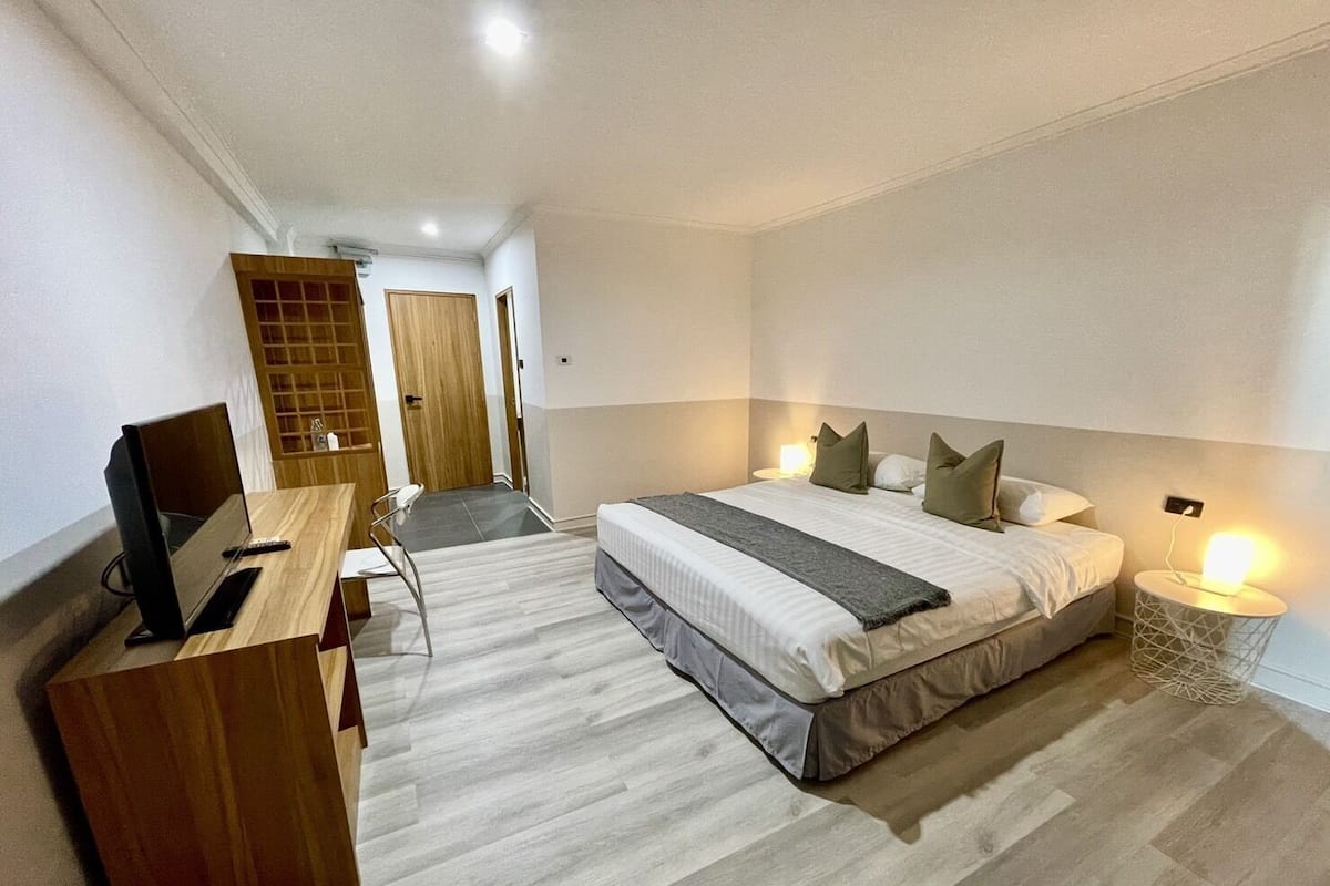 Una habitación de hotel moderna con cama, mesita de noche, escritorio y silla.