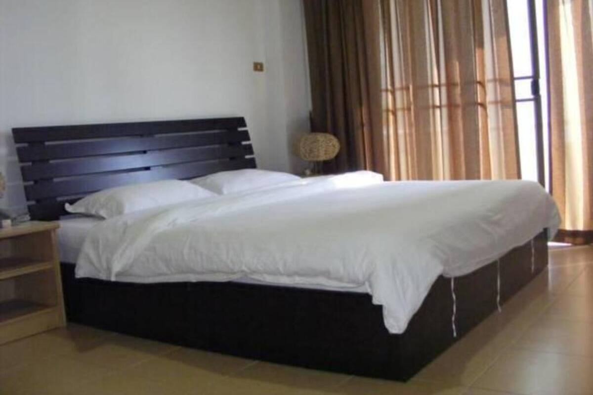 A bedroom with a bed, a nightstand, a lamp, and a window with curtains.