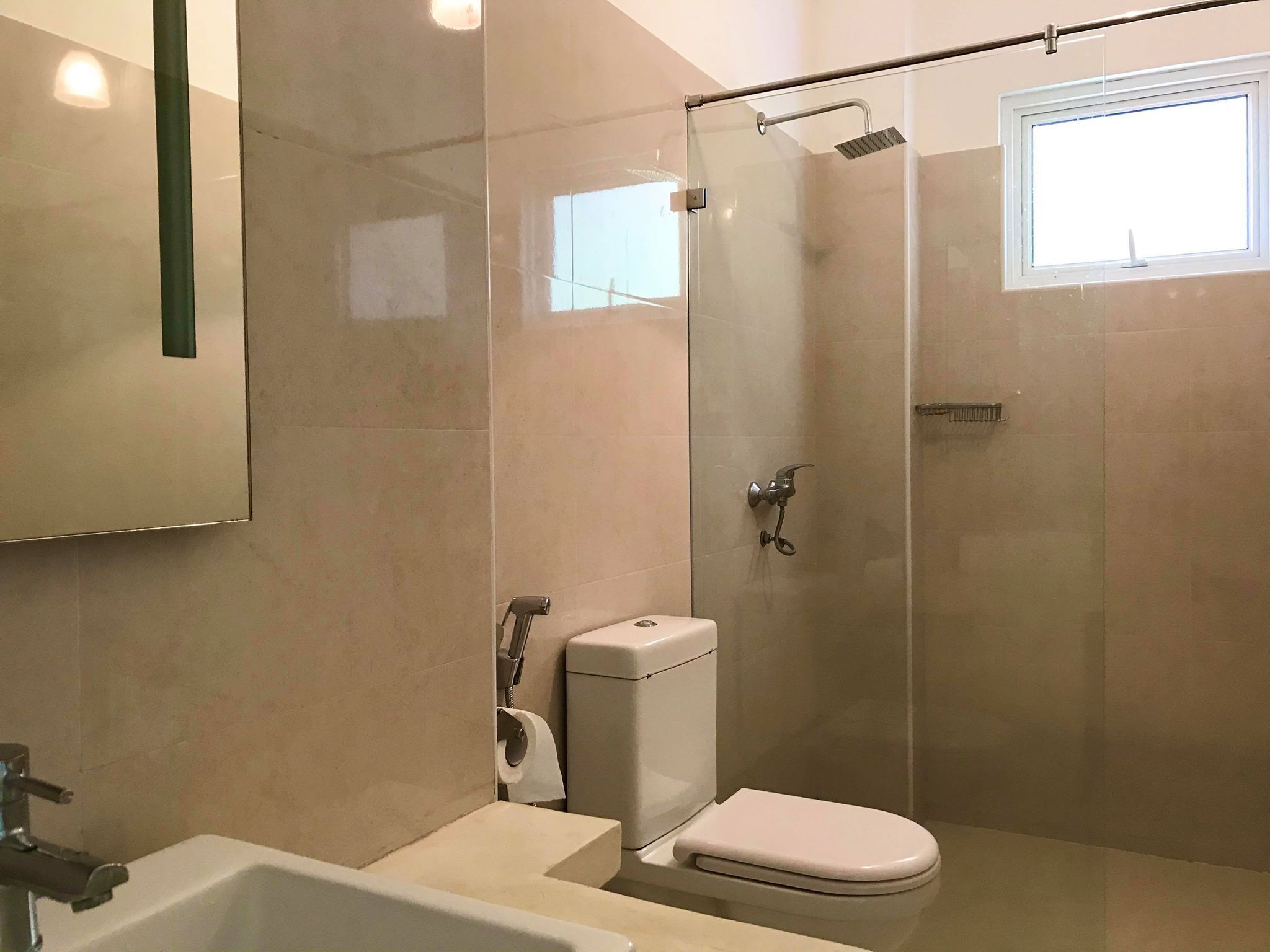 A modern bathroom with a glass-enclosed shower, a toilet, and a sink.
