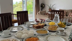 Une table à manger dressée avec différents plats, et un tableau accroché au mur.