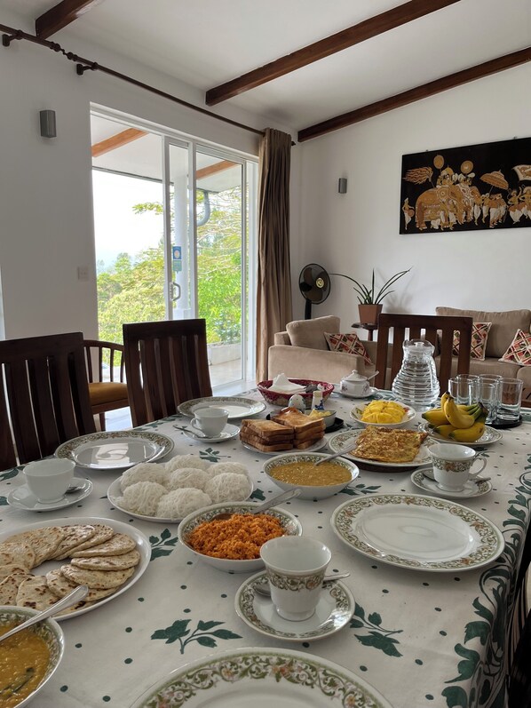 A dining table set with various dishes and a painting on the wall. - Amandari Holiday Villa (Kandy)