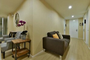 A living room with a sofa, a small table, and a mirror on the wall. - Icheck Inn Residence Sukhumvit 1 (Bangkok)