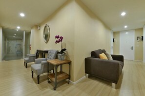 A modern living room with a sofa, armchairs, a coffee table, and a potted plant. - Icheck Inn Residence Sukhumvit 1 (Bangkok)