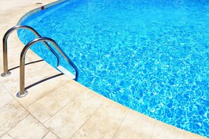 A swimming pool with clear blue water and a metal ladder on the left side. - Icheck Inn Residence Sukhumvit 1 (Bangkok)