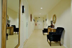 A hotel corridor with a wooden floor, a reception desk, and a seating area with chairs. - Icheck Inn Residence Sukhumvit 1 (Bangkok)