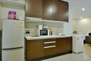 A modern kitchen with a refrigerator, microwave, sink, and wooden cabinets. - Icheck Inn Residence Sukhumvit 1 (Bangkok)