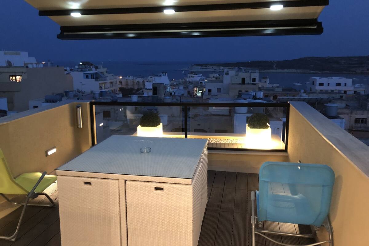 A balcony with a view of a coastal town at dusk.