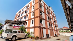 A multi-story residential building with balconies, a sign for 'GRANNYLLA RESIDENCE CHARDERENG', and a parked pickup truck. - Grannylla Residence Charoenkrung (Bangkok)