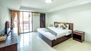 A modern bedroom with a large bed, a desk, and a sliding glass door leading to an outdoor area. - Grannylla Residence Charoenkrung (Bangkok)