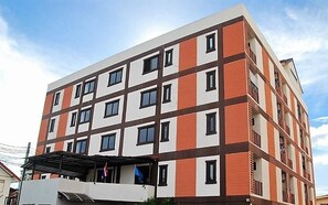 A multi-story building with a modern architectural design, featuring a combination of white and orange panels, and multiple windows per floor. - Grannylla Residence Charoenkrung (Bangkok)
