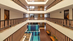 A multi-level hotel interior with a central atrium, a pool area, and a staircase connecting the floors. - Grannylla Residence Charoenkrung (Bangkok)