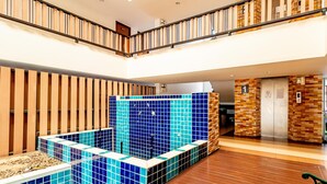 A hotel lobby with a blue-tiled pool area, wooden flooring, and a staircase leading to an upper level. - Grannylla Residence Charoenkrung (Bangkok)