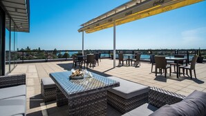 A rooftop terrace with outdoor seating, a pool view, and a Coca-Cola branded canopy. - Hotel Dolphin (Senec)
