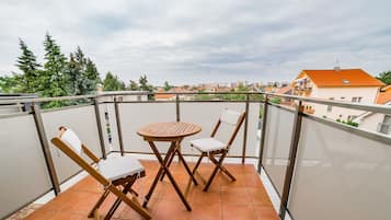 Un balcón con una mesa y dos sillas, con vistas a una zona residencial con casas y árboles.
