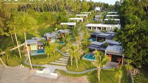 Un resort con villas modernas, piscinas y abundante vegetación.