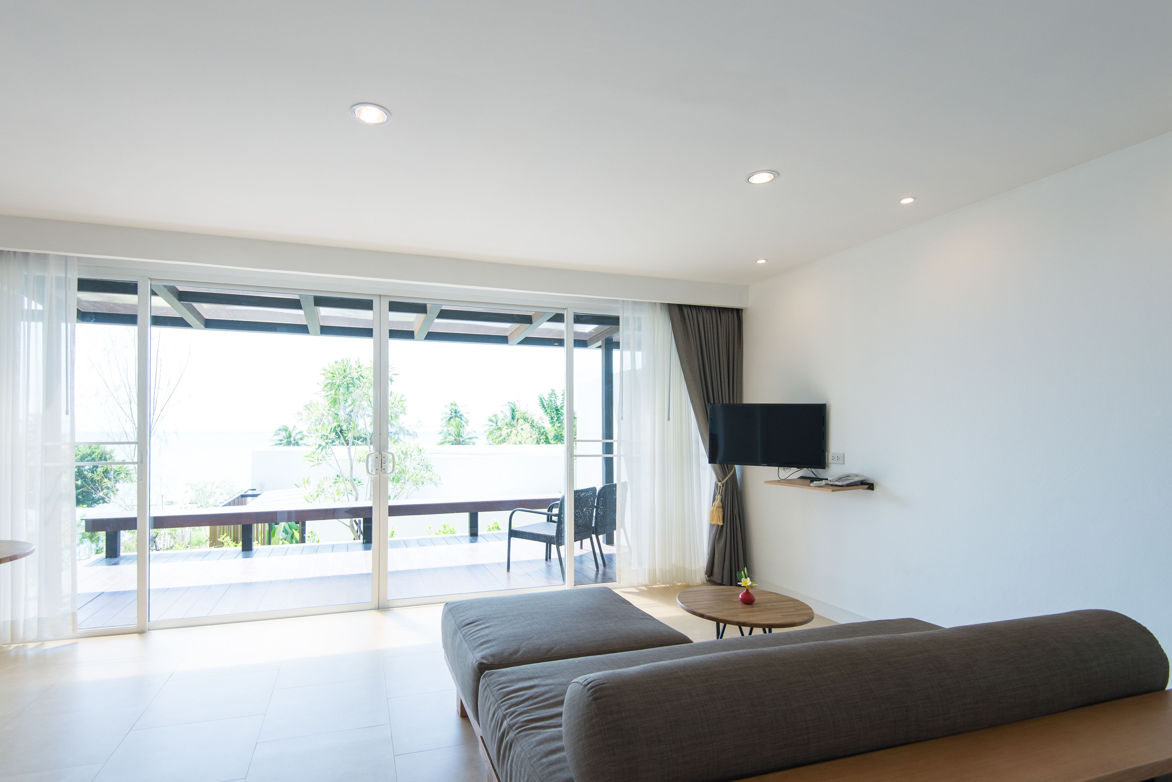 A modern room with a sofa, a small table, and a TV mounted on the wall.