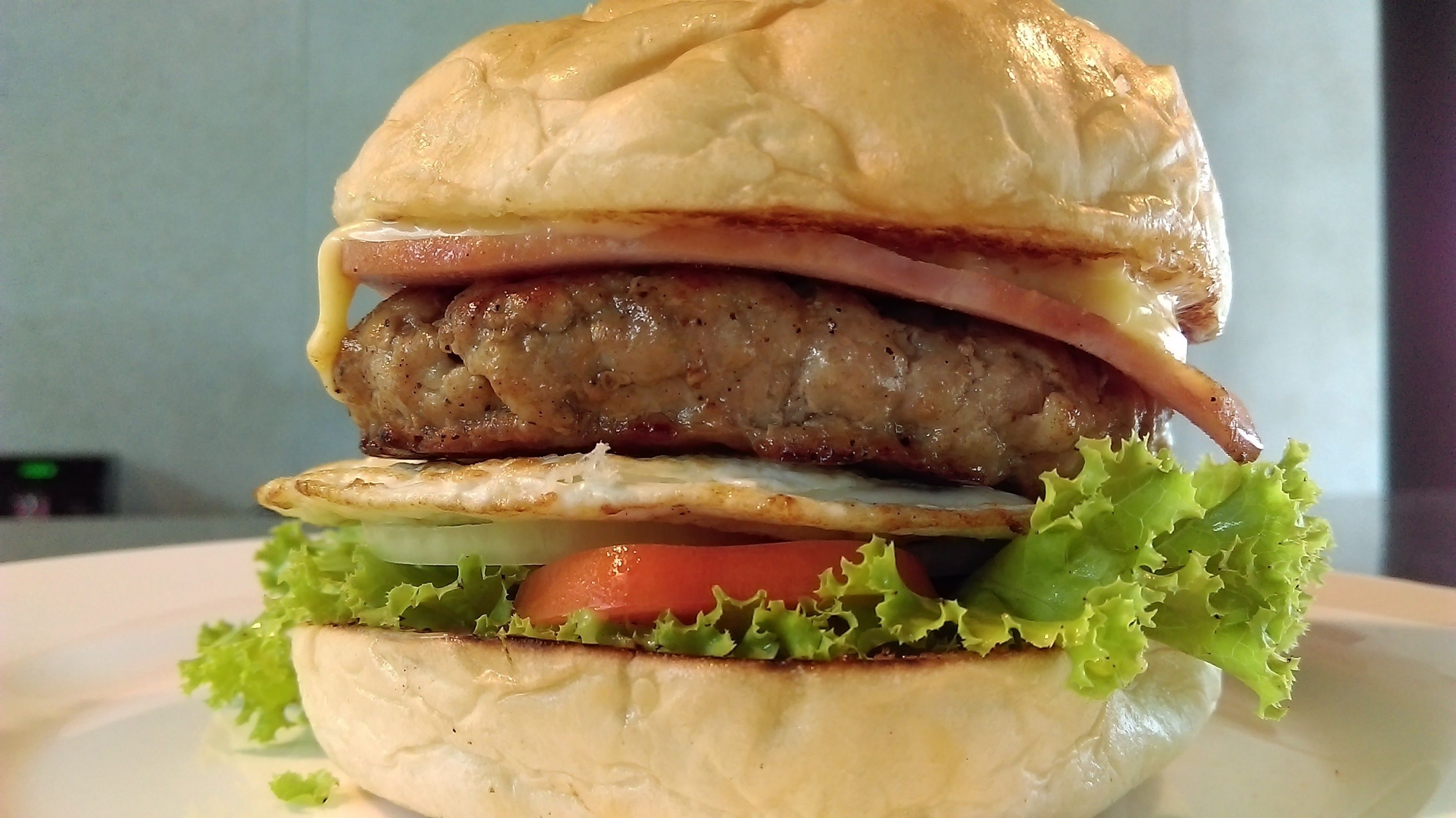 A hamburger with lettuce, tomato, and a fried egg on a bun.