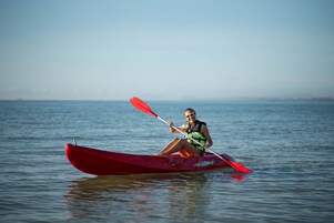 A person in a red kayak on calm water.