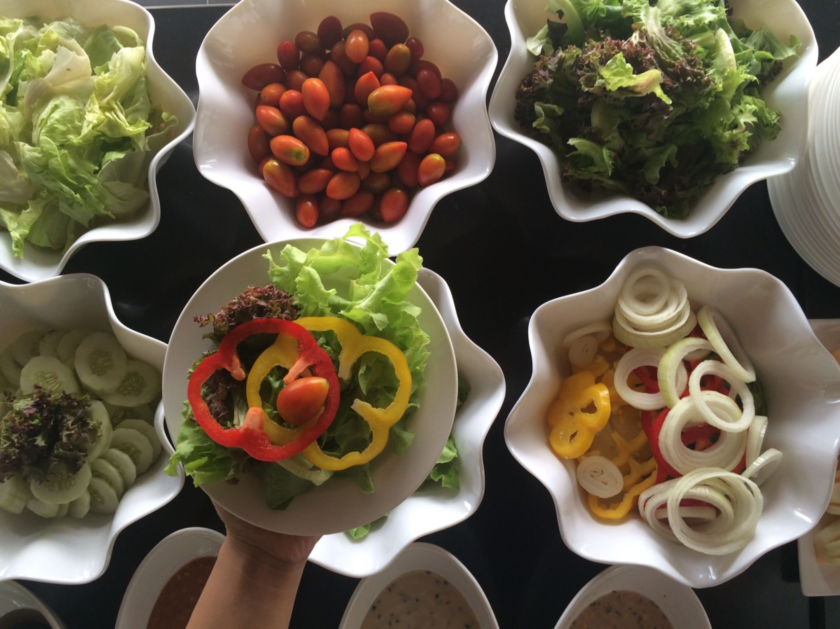 Una mesa con varios recipientes que contienen ensaladas y verduras variadas.