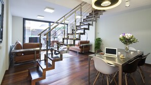 A modern living room with a staircase, a dining area with a laptop, and a vase of flowers. - MSB Pool with Terrace (Barcelona)