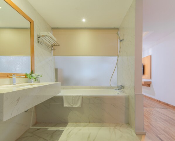 Un baño moderno con piso de mármol, una bañera, ducha y tocador con espejo y una planta pequeña.