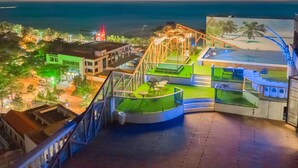 Una terraza en la azotea con piscina, zona de estar y vista al océano.