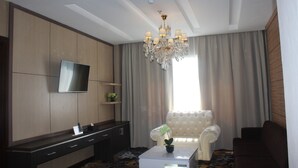 Een moderne woonkamer met een flatscreen televisie, een kroonluchter, een bank en een salontafel.