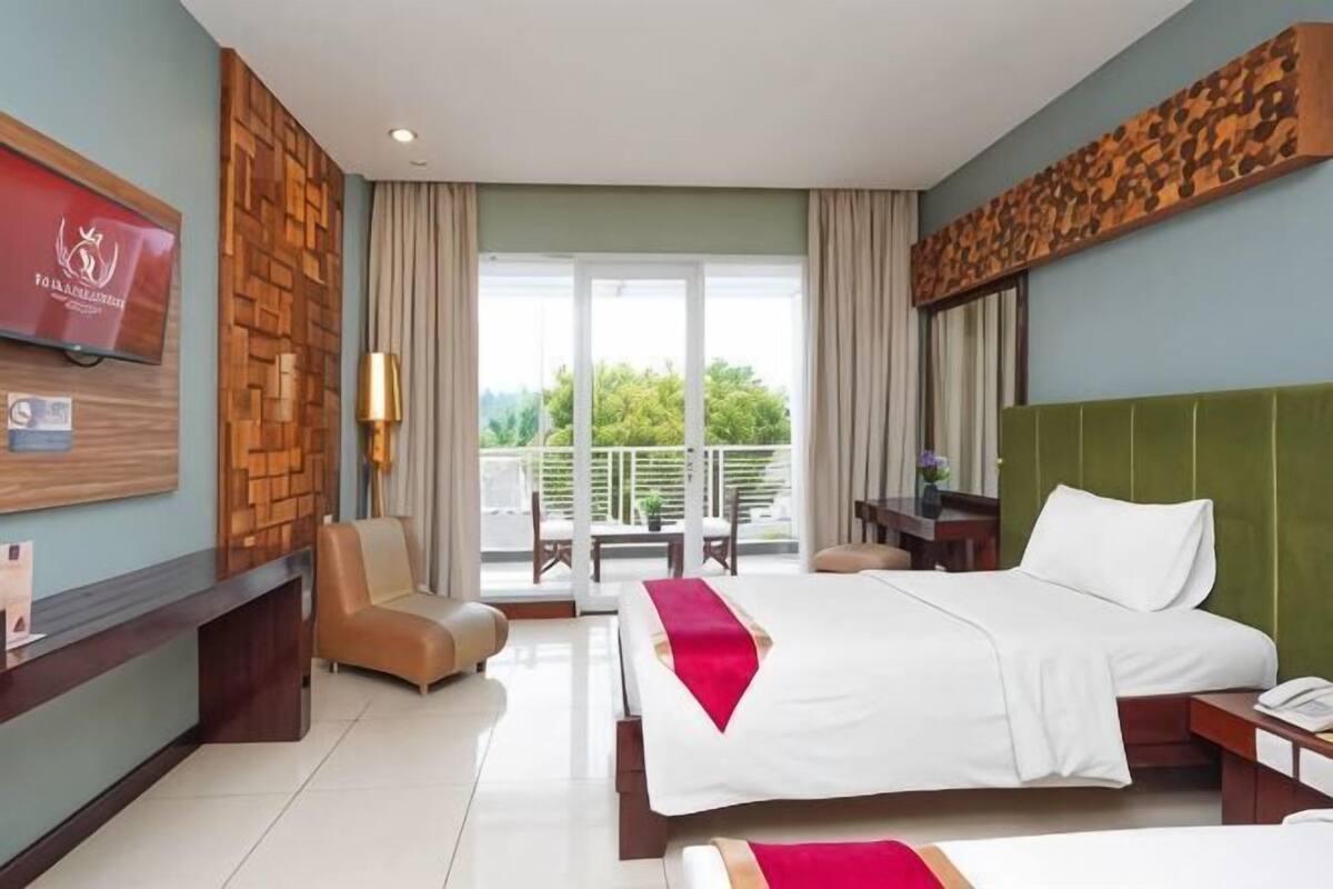 Une chambre d’hôtel avec un lit, une télévision, une chaise, un balcon et une vue sur la verdure.