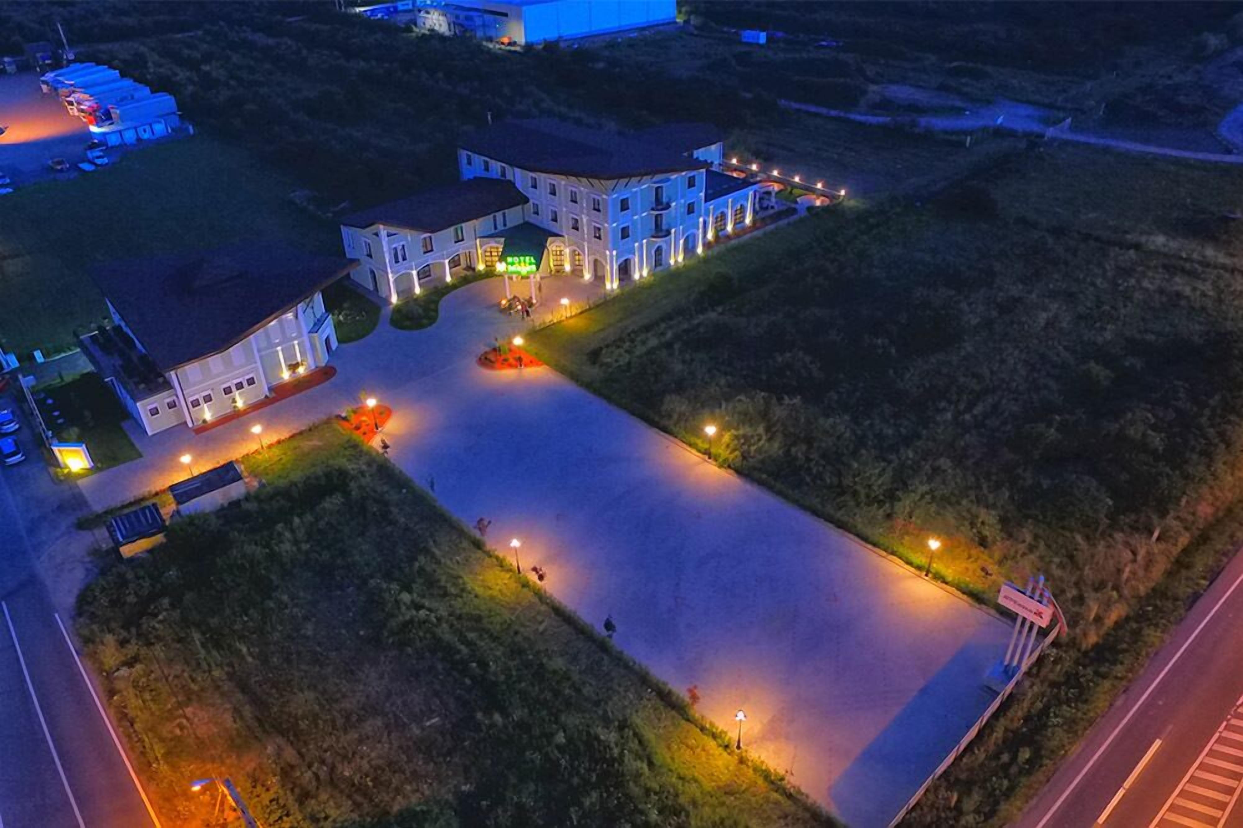 Ett flygbildsbild av ett hotell med en central innergård, omgivet av byggnader med upplysta fönster.