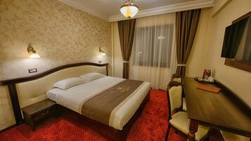 Una habitación de hotel con cama, mesitas de noche, escritorio y una silla.