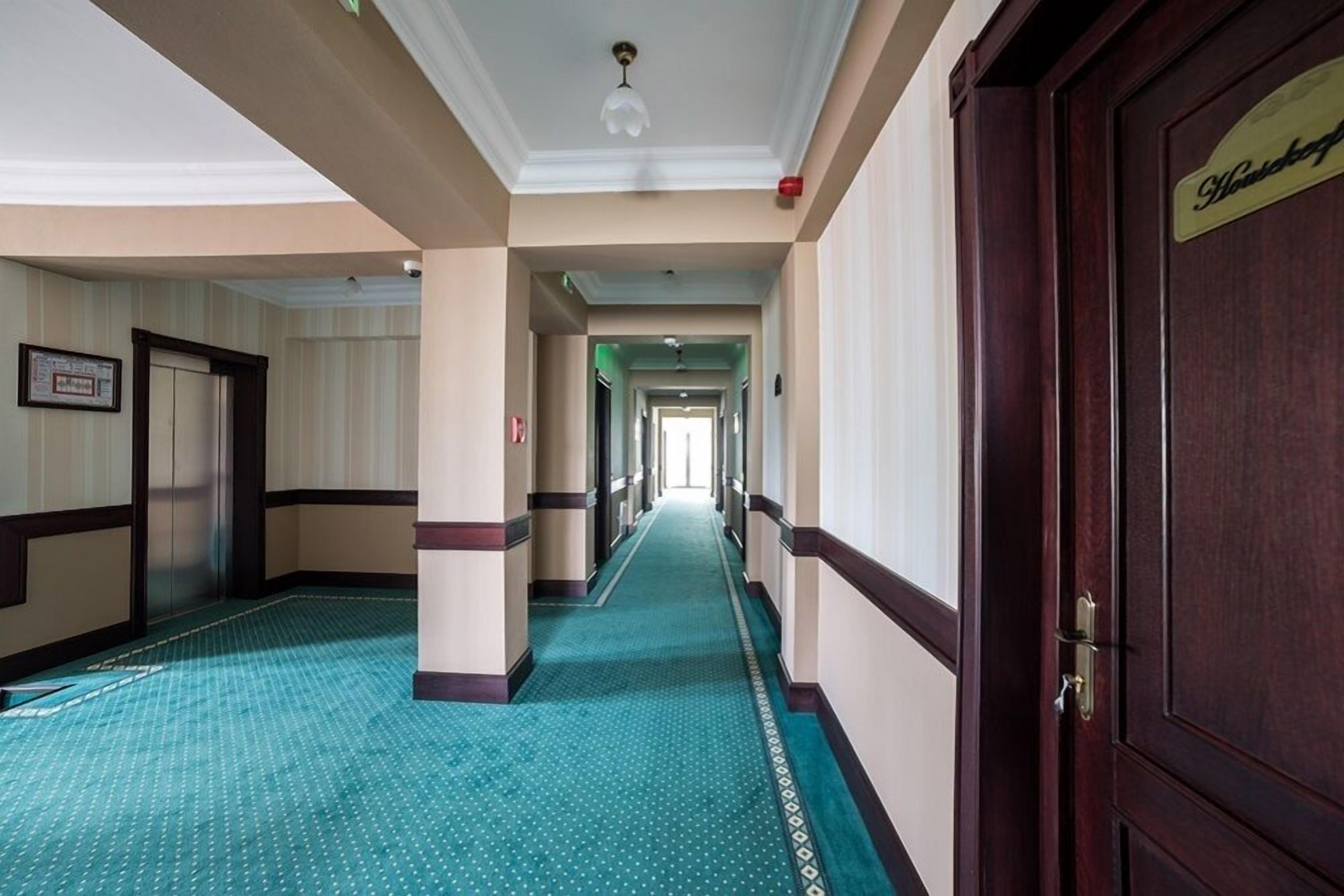 Un pasillo de hotel con suelo a cuadros, puertas de madera y un cuadro enmarcado en la pared.