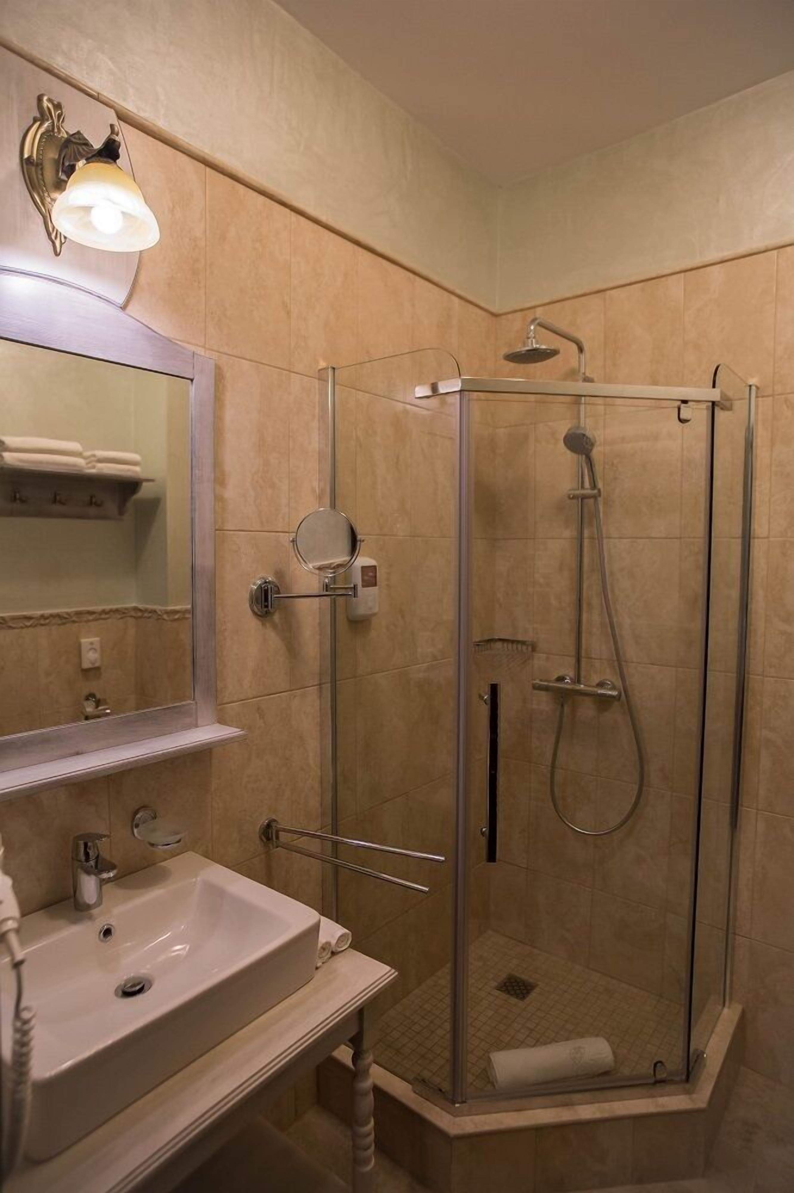 A bathroom with a glass-enclosed shower, a sink with a mirror, and a towel rack.